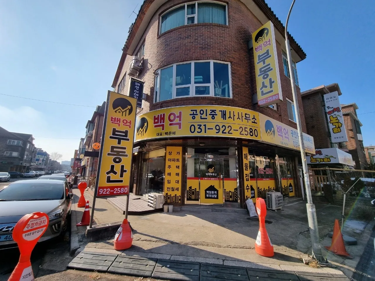 모퉁이 건물 1층의 백억부동산 매장과 세로 간판